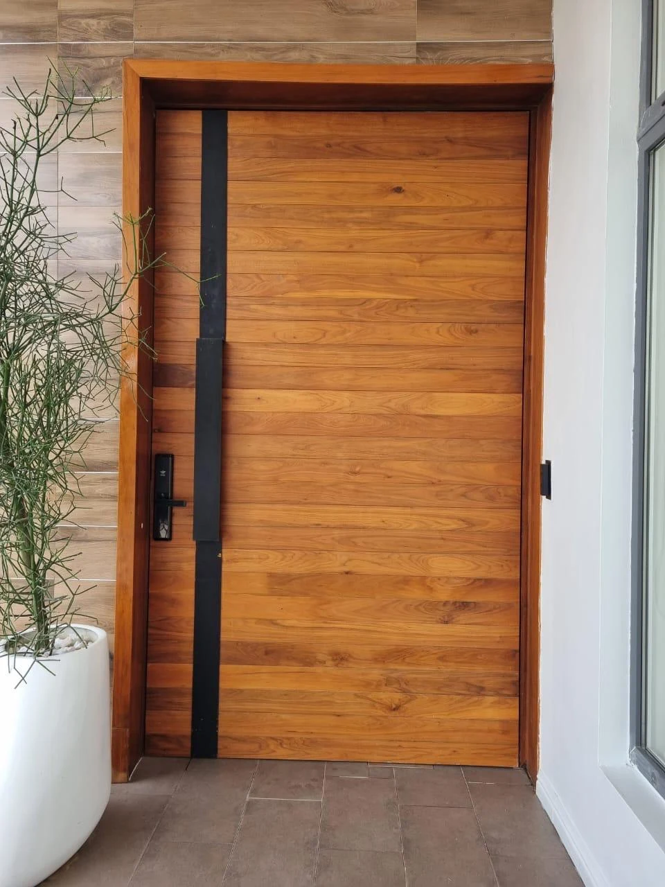 Wood finish entrance door with a black vertical feature